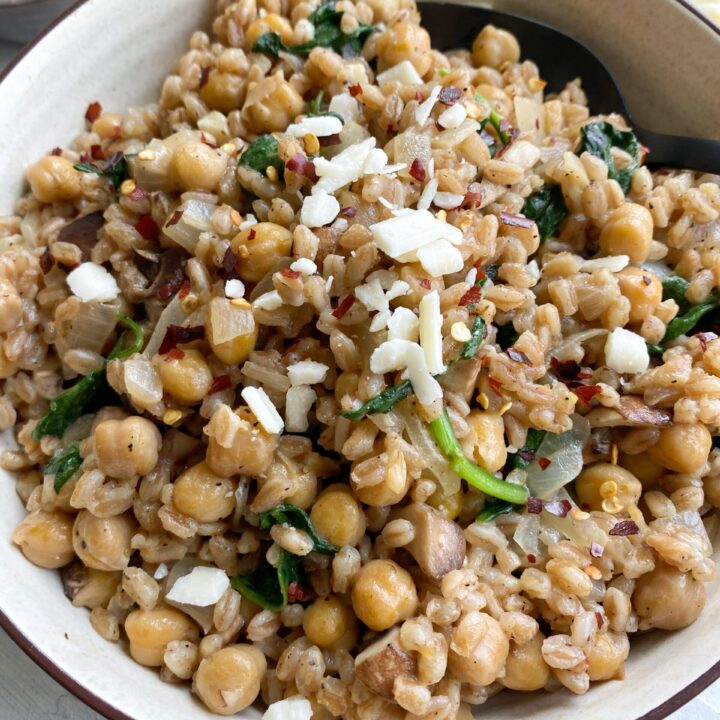 Close up showing a white bowl of Cheesy Chickpeas and Farro.
