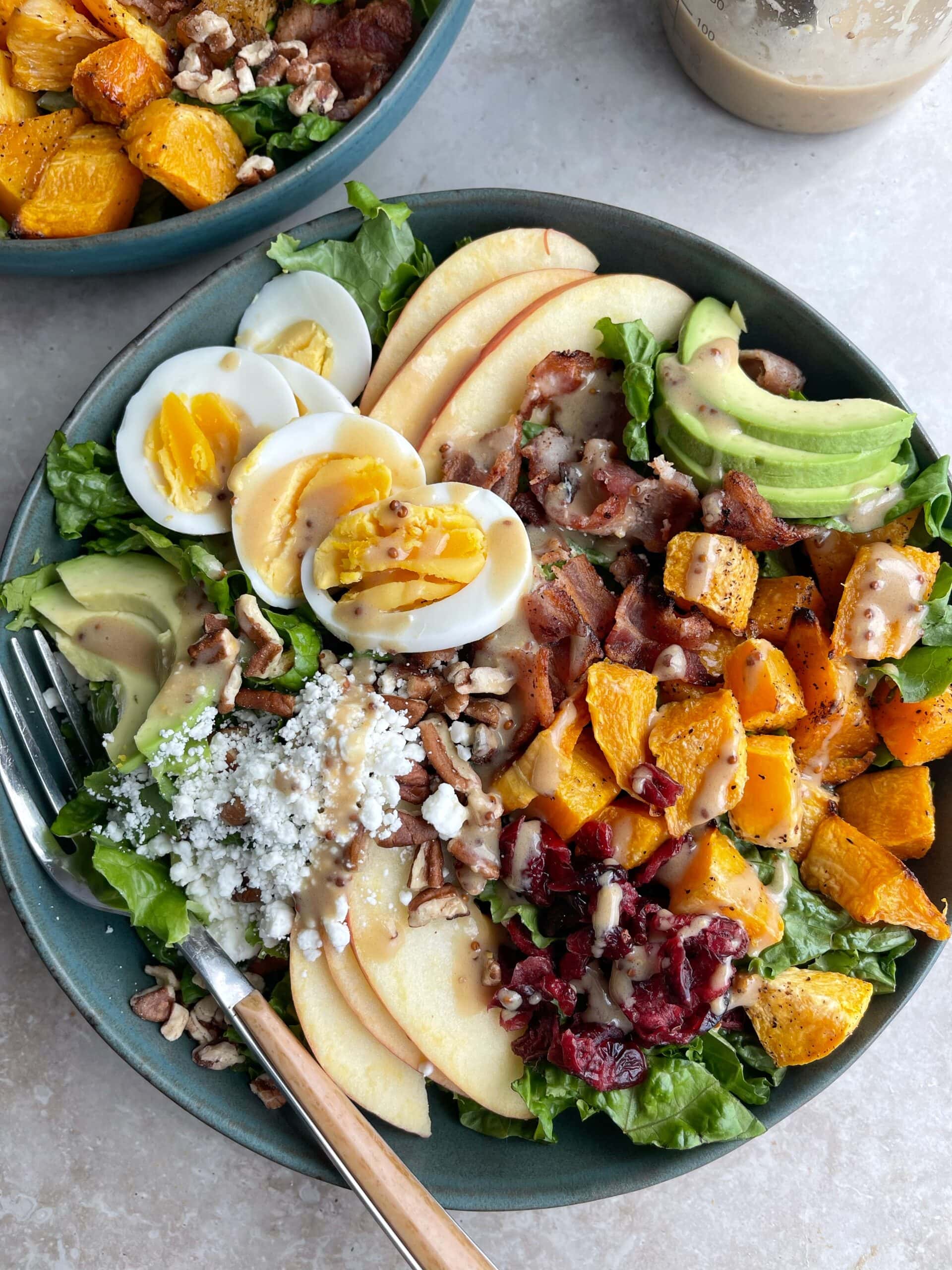 Harvest Cobb Salad close up with boiled eggs, avocado, bacon, goat cheese, butternut squash and apple.